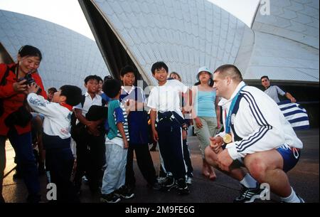 US Gold Medalist Rulon Gardner (Right, squatting) meets a group of Chinese Nationalist at the Sydney Opera House following a photo shot with Sports Illustrated. Mr. Gardner won the Gold Medal in the 130kg Greco Roman wrestling class during the Sydney 2000 Olympics. Base: Sydney Opera House State: New South Wales Country: Australia (AUS) Stock Photo