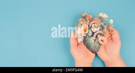 Hands holding human heart with flowers, love and emotion concept, good hearted person, help and charity Stock Photo