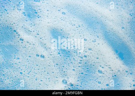 White foam mousse on a blue background. Concept for foaming products, cosmetics or cleaning products. Stock Photo