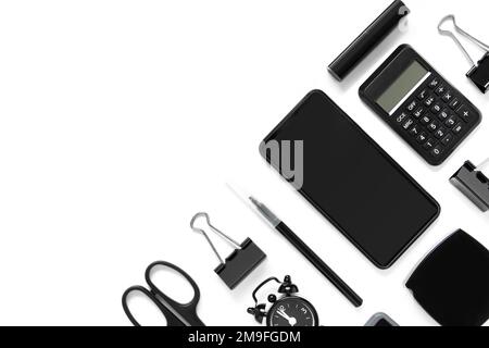Collection of office accessories in black on white background with copy space. Smartphone, calculator, alarm clock, scissors, lipstick, watches. Top v Stock Photo