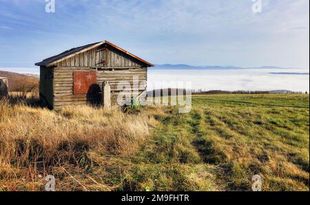 Old hut over clouds in pasture mountain landscape. Stock Photo