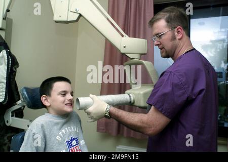 Red Cross Volunteer Morgan Bowker, 52nd Dental Squadron, Spangdahlem Air Base, Germany, performs a dental x-ray procedure on 8-year-old, Nicolas Austin at the Bitburg dental clinic. Base: Spangdahlem Air Base State: Rheinland-Pfalz Country: Deutschland / Germany (DEU) Stock Photo