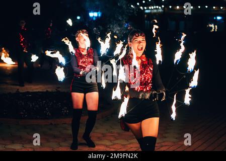 SEMIGORYE, IVANOVO OBLAST, RUSSIA - JUNE 26, 2018: Fire show. Girls dancers spin torches of fire. Dangerous amazing night performance Stock Photo
