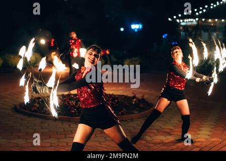SEMIGORYE, IVANOVO OBLAST, RUSSIA - JUNE 26, 2018: Fire show. Girls dancers spin torches of fire. Dangerous amazing night performance Stock Photo