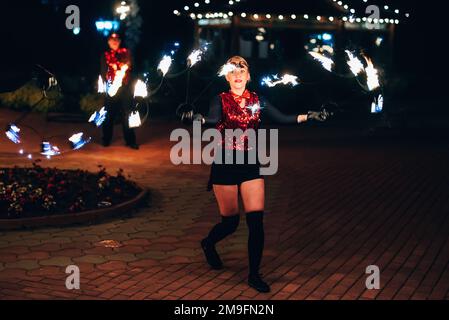 SEMIGORYE, IVANOVO OBLAST, RUSSIA - JUNE 26, 2018: Fire show. The girl spins the fiery torches. Dangerous amazing night performance Stock Photo