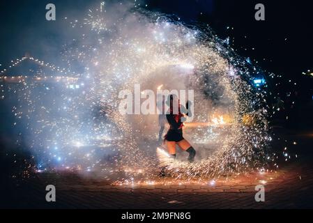SEMIGORYE, IVANOVO OBLAST, RUSSIA - JUNE 26, 2018: Fire show. Girl spins fiery sparkling torches. Dangerous amazing night performance Stock Photo