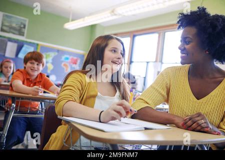 Learning, education and teacher help student with assignment in elementary school. Classroom support, scholarship and happy black woman or educator Stock Photo