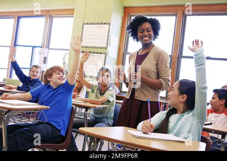 School, tutor and students raise their hands to ask or answer an academic question for learning. Diversity, education and primary school kids speaking Stock Photo