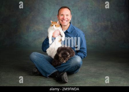 Studio portrait of smiling man with two cats Stock Photo - Alamy