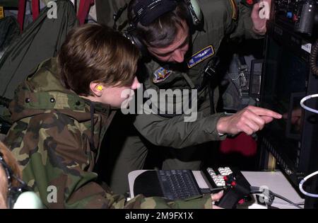 MASTER Sergeant David Gonzales an imagery analyst from the 152nd Air Wing, Nevada Air National Guard gives US Army Private First Class Stephanie E. Shick, an imagery analyst from Fort Wainwright, Alaska, a closer look at the Scathe View system aboard a Air National Guard C-130 Hercules aircraft. US Air force and US Army personnel received training on the Scathe View system during Exercise NORTHERN EDGE 2001. The system can capture imagery on the ground from up to 17,000 ft in the air and can instantly transmit the imagery to ground forces. Subject Operation/Series: NORTHERN EDGE 2001 State: Ne Stock Photo