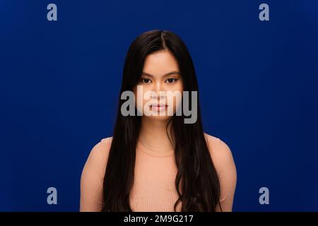 Long haired asian woman looking at camera isolated on navy blue Stock Photo