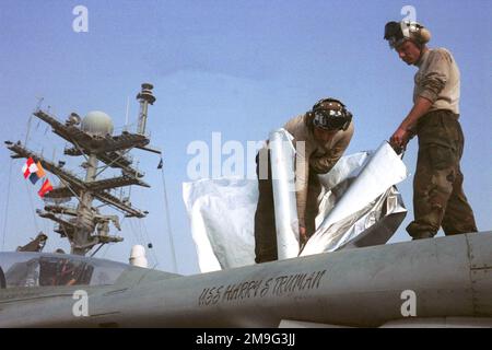 US Navy Aviation Machinist's Mate Third Class Daniel Elliott and US Navy Aviation Structural Mechanic Third Class Jason Grossett cover the canopy of an F-14 Tomcat aircraft from Fighter Squadron Thirty-Two (VF-32), with heat shields to keep sand from corroding the aircraft during USS HARRY S. TRUMAN (CVN 75)'s transit through the Suez Canal. Base: USS Harry S. Truman (CVN 75) Stock Photo