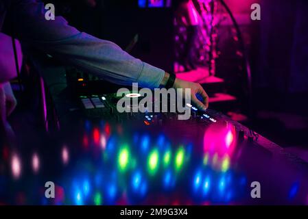 hands DJ mixing and playing music on a professional controller mixer in a nightclub Stock Photo