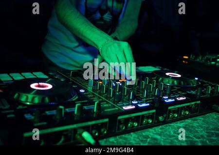 hands DJ mixing and playing music on a professional controller mixer Board in a nightclub Stock Photo