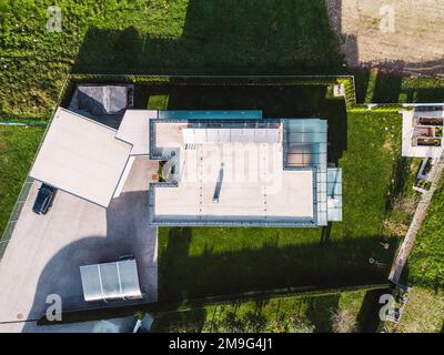 Top down view at the lot of a modern family home with flat rooftop and solar panels on it Stock Photo