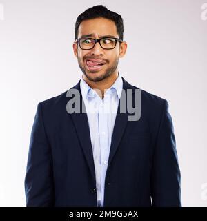 Theres always time to be a bit silly. a handsome man standing alone against a grey background in the studio and making funny faces. Stock Photo