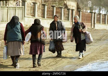 Salaj County, Romania, approx. 1999.Women walking on the unpaved muddy road through their village in wintertime. Stock Photo