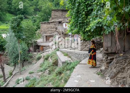 An adult woman wearing traditional attire on the street of a Kalash village, Bumburet Valley, Pakistan Stock Photo