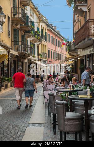 Tourists strolling and having morning coffee in the street cafes in Peschiera, Lake Garda, Northern Italy Stock Photo