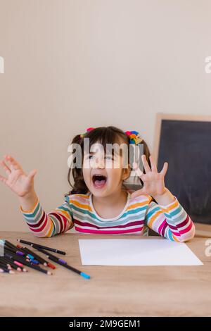 a happy cute little girl in a drawing lesson raises her hand at the top Stock Photo