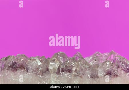 Light pale colored Amethyst quartz crystals in raw mineral form on a plain purple background. Conceptual image with copy space. Stock Photo