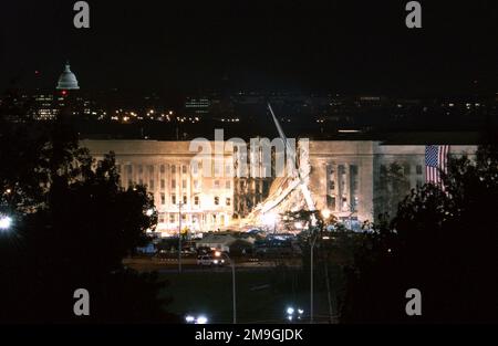 The huge American flag visible to the right of the damaged area is the garrison flag sent from the US Army Band at nearby Fort Myer, Virginia. It is the largest authorized (20' x 38') flag for the military. 3rd Infantry soldiers and fire fighters unfurled the flag over the side. Each night floodlights illuminated it. The impact area is where the hijacked American Airlines Flight 77, a Boeing 757-200 deliberately crashed into the building the day before. The Pentagon attack followed a similar attack, two hijacked passenger planes flown into the twin towers of the New York World Trade Center, on Stock Photo