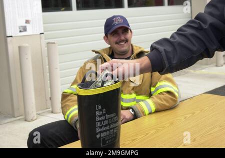 A Kingsley Field Airport fireman watches as donations as dropped into a firemans boot. The donations are for the families of the firemen killed in the World Trade Center collapse on September 11, 2001. The collapse due to terrorist flying two large passenger aircraft into the buildings; killing all in the planes and thousands in the building. Base: Kingsley Field State: Oregon (OR) Country: United States Of America (USA) Scene Major Command Shown: ANG Stock Photo