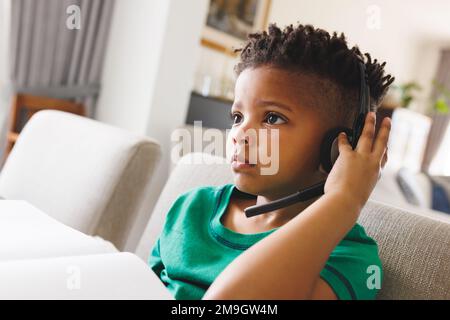 Happy african american boy sitting at table, having online lesson Stock Photo