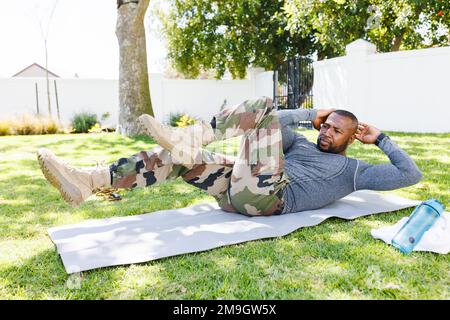 Happy african american man wearing military uniform exercising in backyard Stock Photo