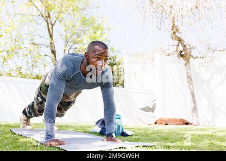 Happy african american man wearing military uniform exercising in backyard Stock Photo