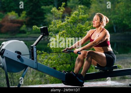 Woman exercising on rowing machine outdoors, Bainbridge Island, Washington, USA Stock Photo