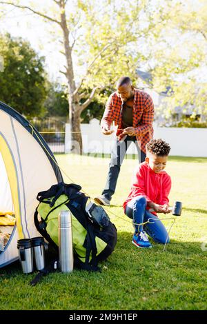 Happy african american father and son pitching tent in their backyard Stock Photo