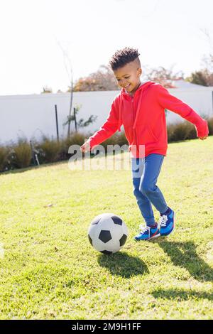 Happy african american boy playing football in backyard Stock Photo