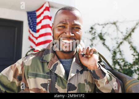 Portrait of happy african american man wearing military uniform holding bag and returning home Stock Photo
