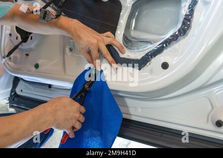 Mechanic man using wedge unpacking vehicle door part for checking damage in garage workshop Stock Photo