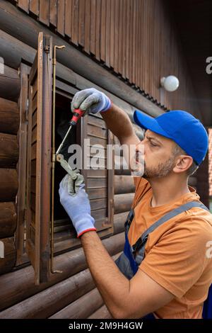 Repairman fixing wooden window shutter by using screwdriver Stock Photo