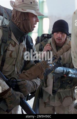 US Navy Corpsman Second Class Gartman, carrying an M-16 and a Barrett M82A1, a member of Headquarters Company, Battalion Landing Team 3/6, 26th Marine Expeditionary Unit (Special Operations Capable) waits at Kandahar International Airport, Kandahar, Afghanistan, to board a Marine Corps KC-130 on a mission in support of OPERATION ENDURING FREEDOM. In the background a Marine carries an M-136 Light Anti-Armor Weapon. Subject Operation/Series: ENDURING FREEDOM Base: Kandahar International Airport Country: Afghanistan (AFG) Scene Major Command Shown: 26th MEU (SOC) Stock Photo