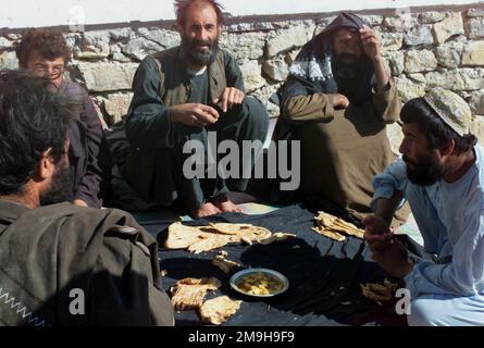 Members of the Anti-Taliban Forces (ATF) have lunch at an observation post site where Marines were dispatched to destroy unexploded munitions dropped by coalition air sorties near the Kandahar International Airport, Kandahar, Afghanistan, during OPERATION ENDURING FREEDOM. Subject Operation/Series: ENDURING FREEDOM Base: Kandahar International Airport Country: Afghanistan (AFG) Stock Photo