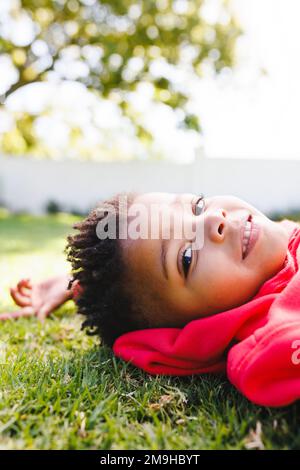 Portrait of happy african american boy laying on grass in backyard Stock Photo