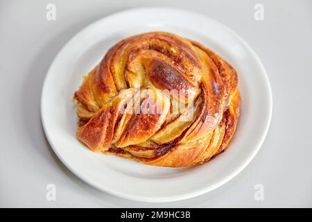Danish cinnamon bun on a white plate Stock Photo
