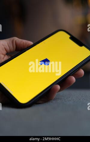 Hand holding a smartphone with PayPal icon on screen. Blue pay pal logo on yellow screen. IPhone with finance, banking app. Amsterdam, Netherlands 202 Stock Photo