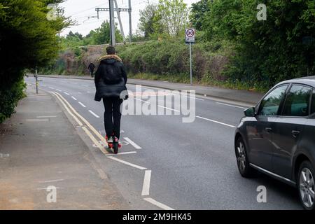 Slough, Berkshire, UK. 4th May, 2022. A young man rides a Neuron e scooter without a crash helmet. The E-Scooter trial rental scheme in Slough run by company Neuron Mobility, has been extended for another two years. The orange scooters are popular, however, e-scooters in general have been criticised as some users speed on the pavements and roads with them causing accidents. Credit: Maureen McLean/Alamy Stock Photo