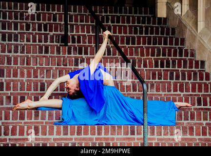 Acrobat in blue dress stretching on staircase, University of Washington, Seattle, Washington State, USA Stock Photo