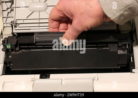 A man changes a toner cartridge in a laser printer. Stock Photo