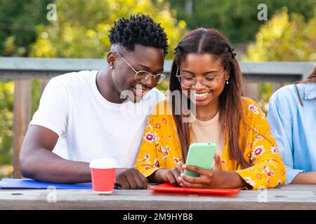 young loving couple checking phone together having coffee and studying - education concept Stock Photo