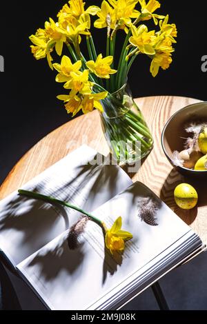 easter eggs, daffodils and magazine on table Stock Photo