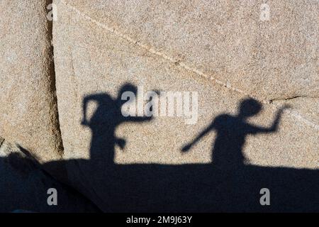 children playing with shadows on a rock in Joshua Tree National park Stock Photo