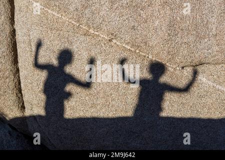 children playing with shadows on a rock in Jushua Tree National park Stock Photo