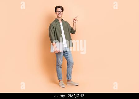 Full length size cadre of young cheerful positive man remote education direct finger point mockup with laptop isolated on beige color background Stock Photo