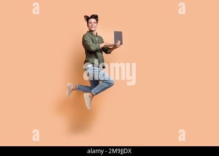 Full body length size cadre of young jumper overjoyed crazy guy hold netbook professional programmer addicted code isolated on beige color background Stock Photo